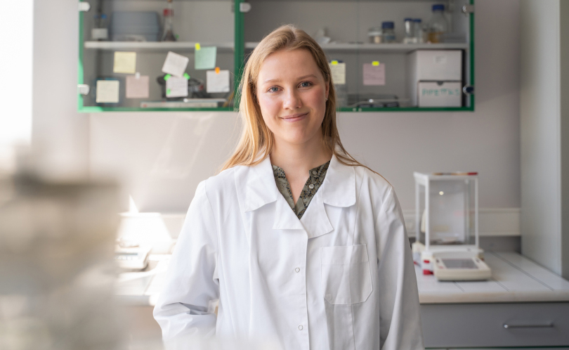 A female scientist in a white lab coat, smiling, standing Viome Labs